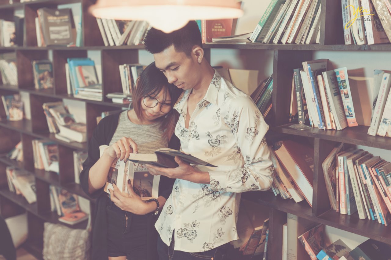 cặp đôi tựa vào nhau đọc sách trong thư viện