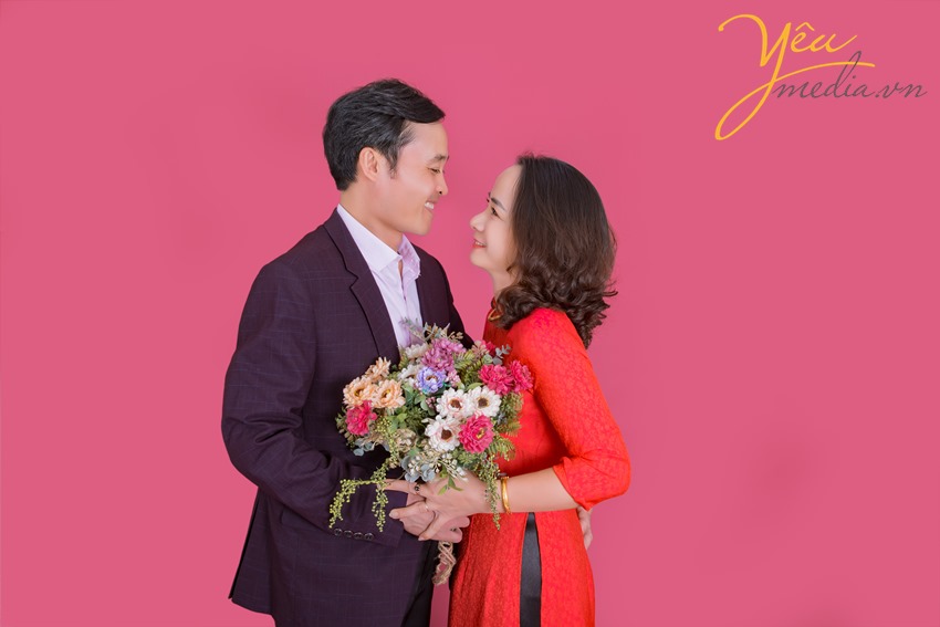 hai vợ chồng nhìn nhau trìu mến chụp ảnh trong studio