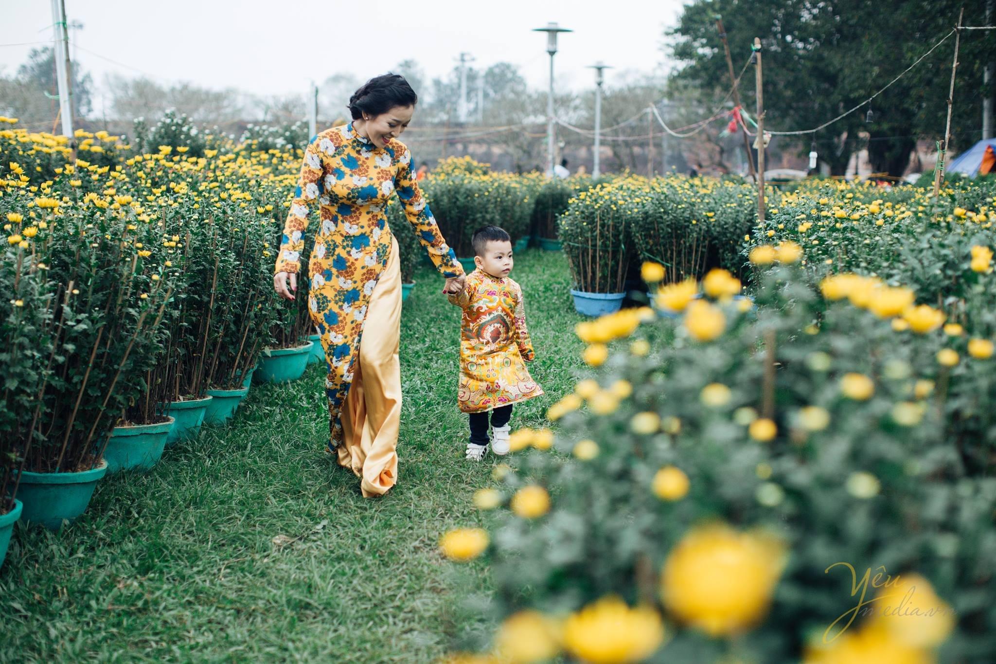 mẹ dăt bé chơi vườn hoa cúc tết chụp ảnh áo dài