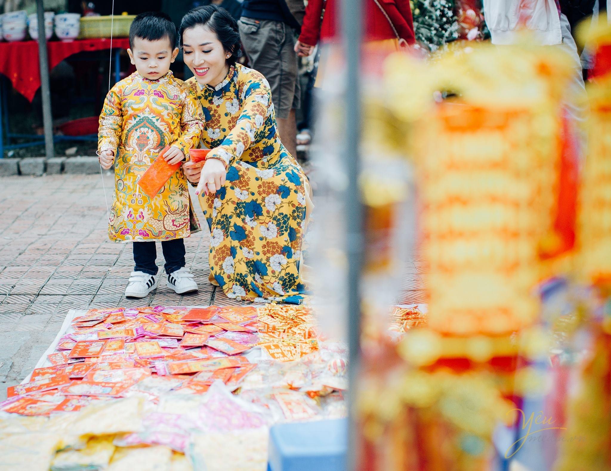 mẹ và bé mặc áo dài tết chụp ảnh bên sạp bán lì xì