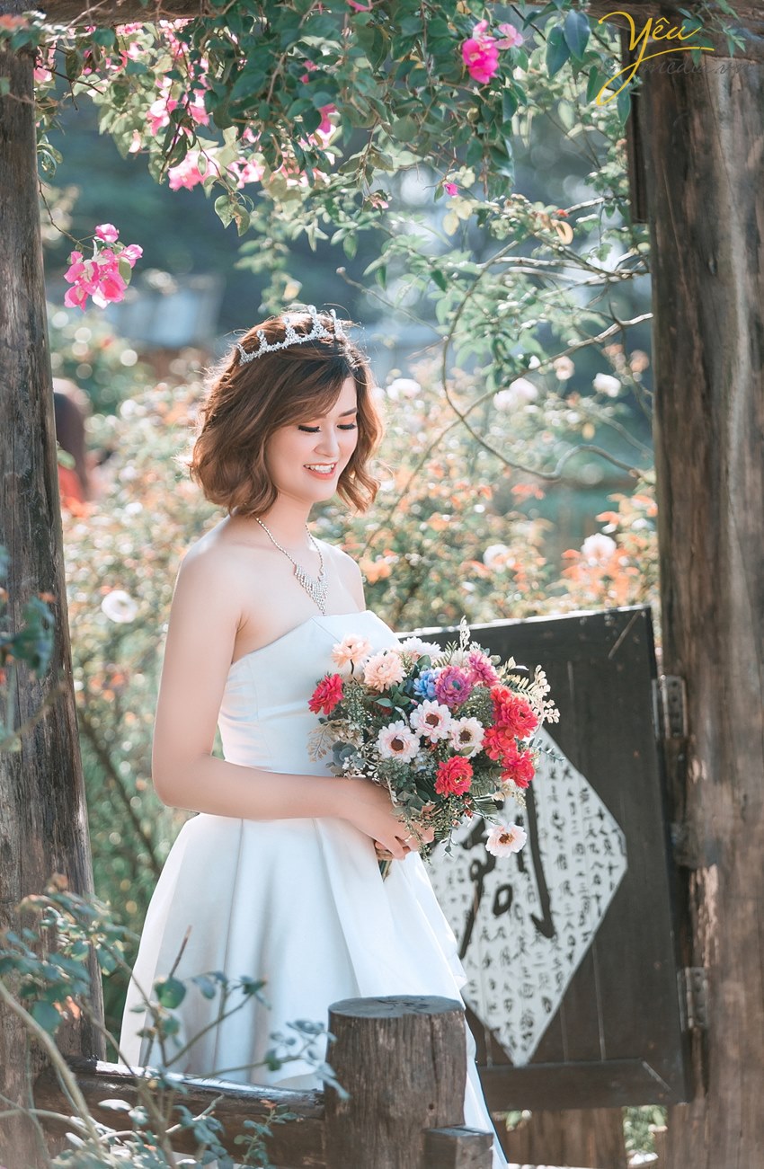 cô dâu cầm hoa xinh đẹp trong bộ váy cưới màu trắng