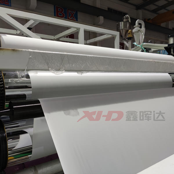 Màng nhựa PVC đang được cán mỏng sau khi ra khỏi khuôn đùn.