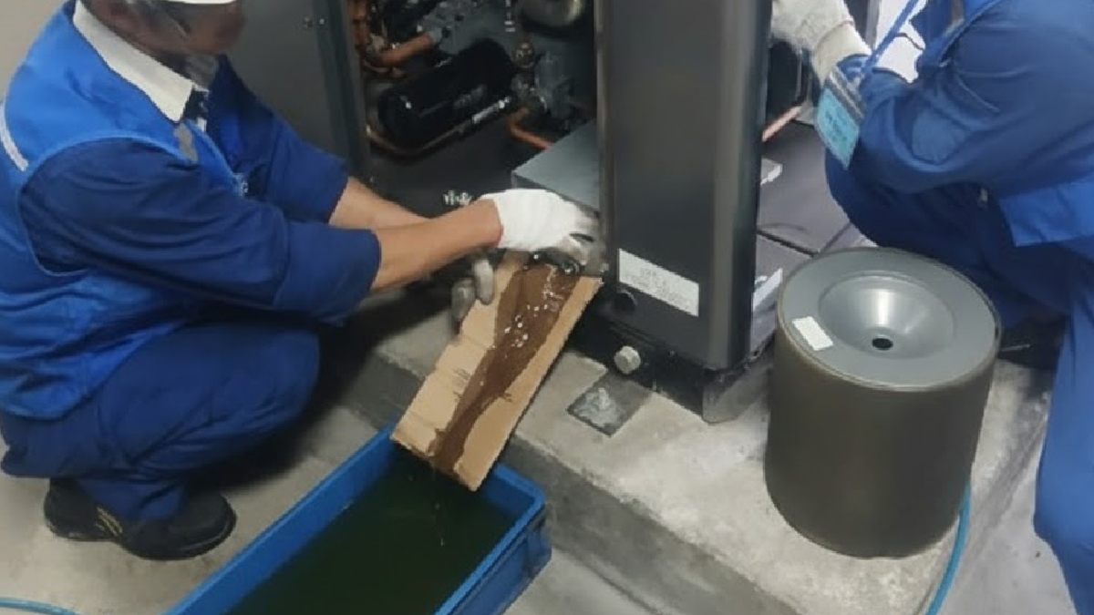 kỹ thuật viên bảo trì thay dầu máy nén khí trong nhà xưởng