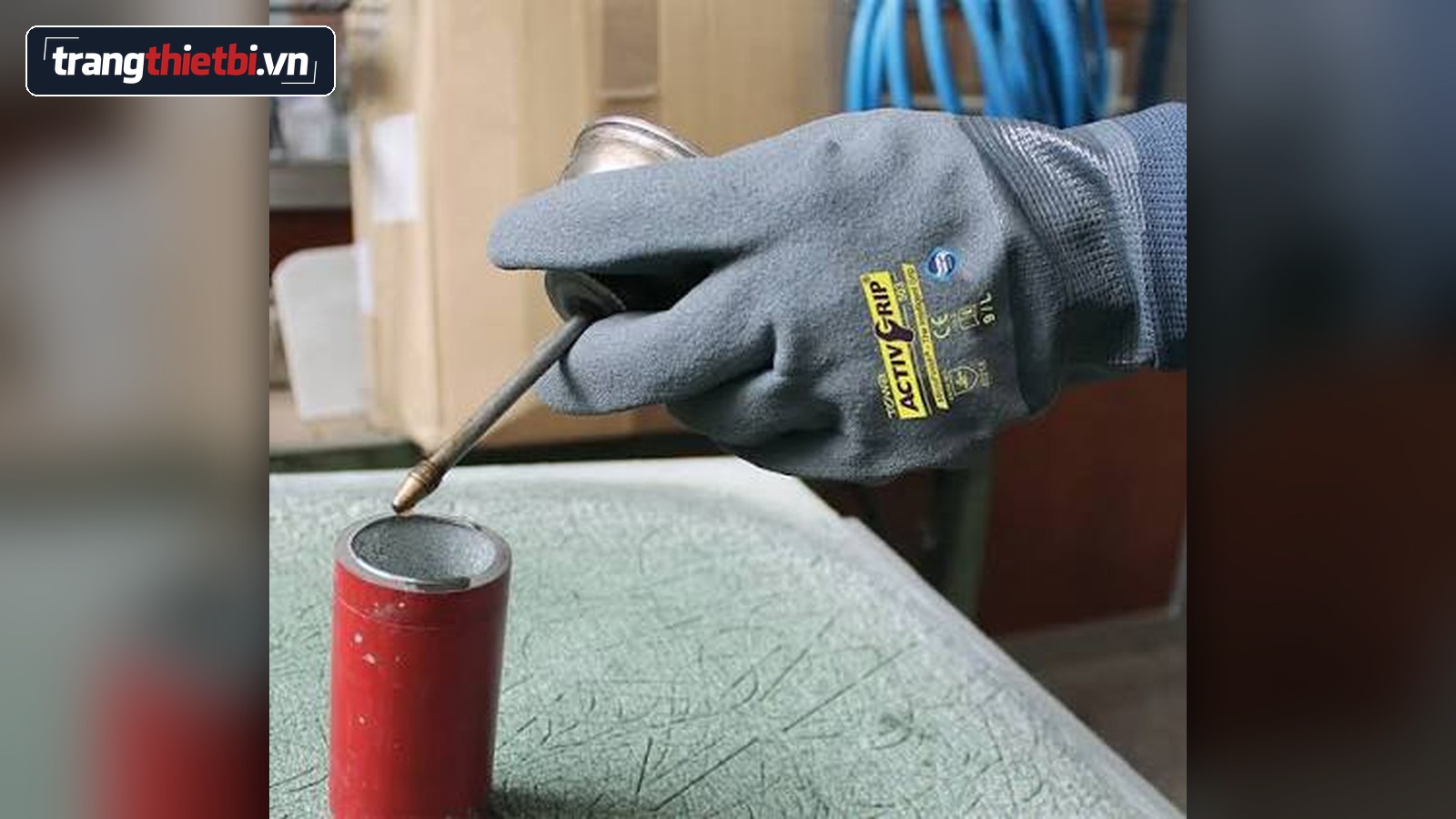 Hình ảnh thực tế công nhân đeo găng tay bảo hộ chống trượt Towa ActivGrip 503 thao tác chính xác với dụng cụ cơ khí và dầu nhớt trong nhà máy