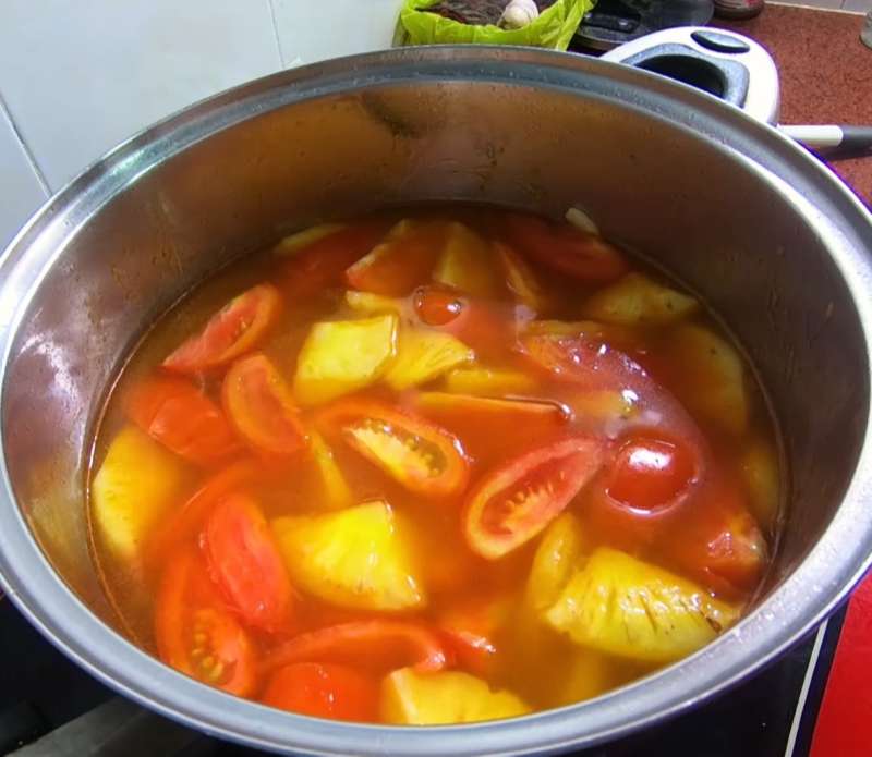 Đun cà chua và dứa để tạo màu và độ chua cho nồi canh đầu cá hồi