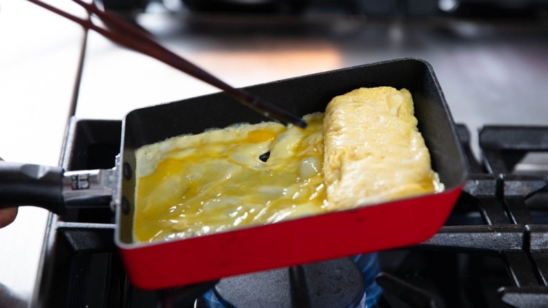 Đổ thêm một lớp trứng mỏng, cuộn lại đến khi gần chín