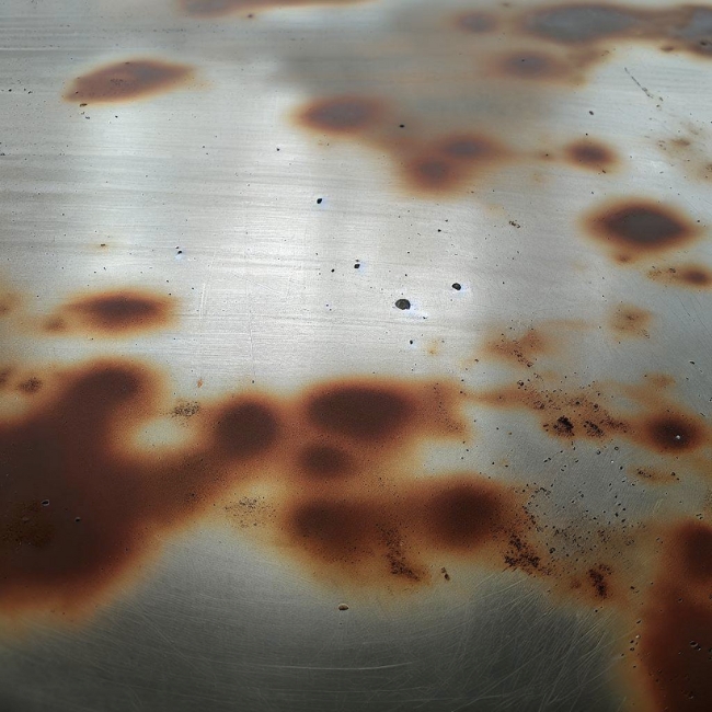 Một bức ảnh của một tấm inox 201 với những đốm gỉ trên đó