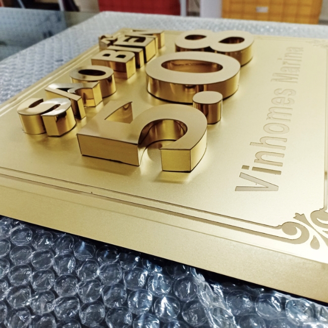 Một biển công ty được làm bằng inox ăn mòn hoa văn và chữ nổi