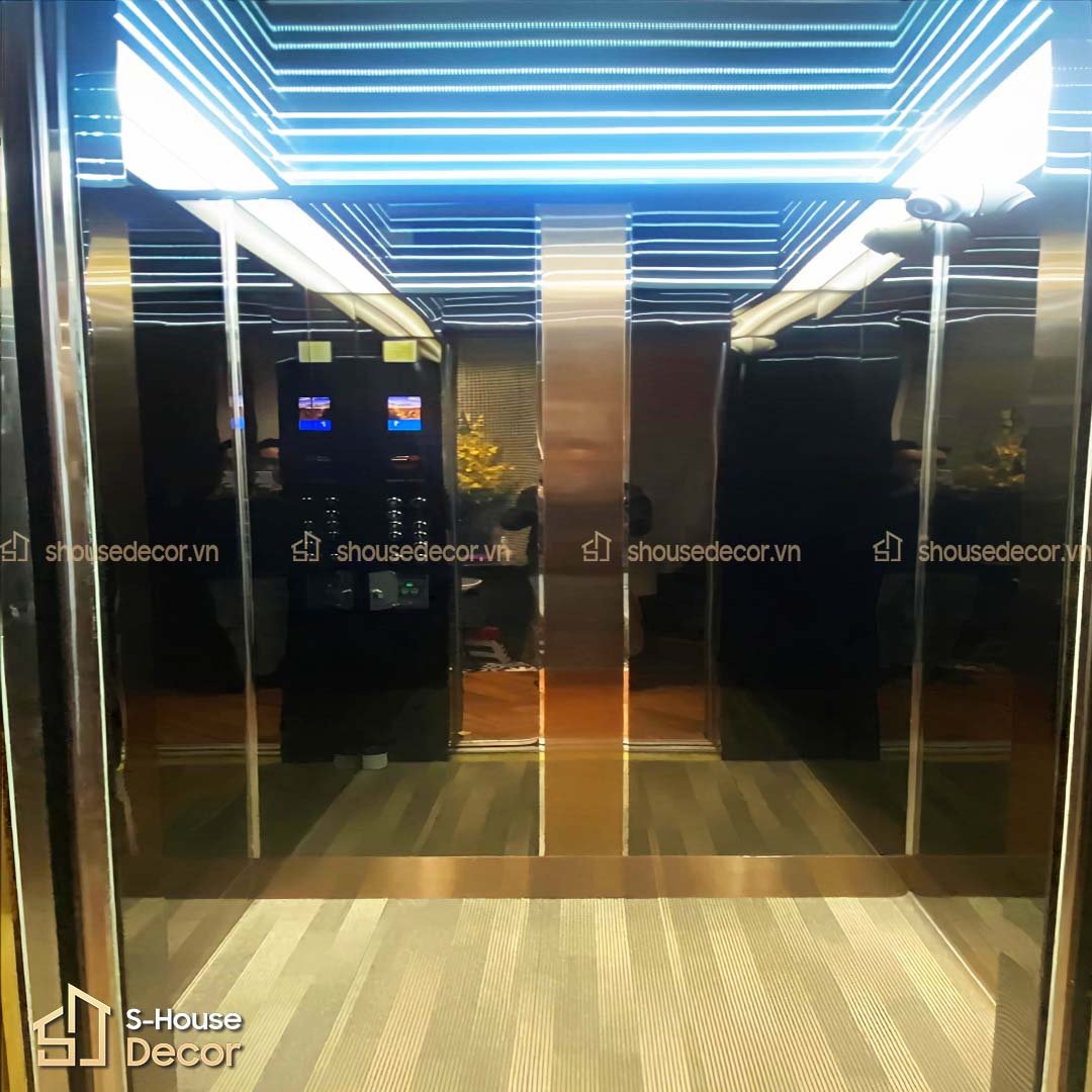 Cabin thang máy sử dụng inox 304 màu vàng gương sang trọng, tạo hiệu ứng phản chiếu ánh sáng và mở rộng không gian.