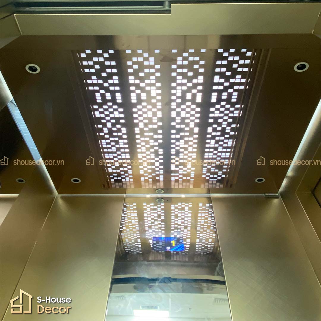 Trần thang máy đục hoa văn inox CNC, ánh sáng LED tỏa đều.