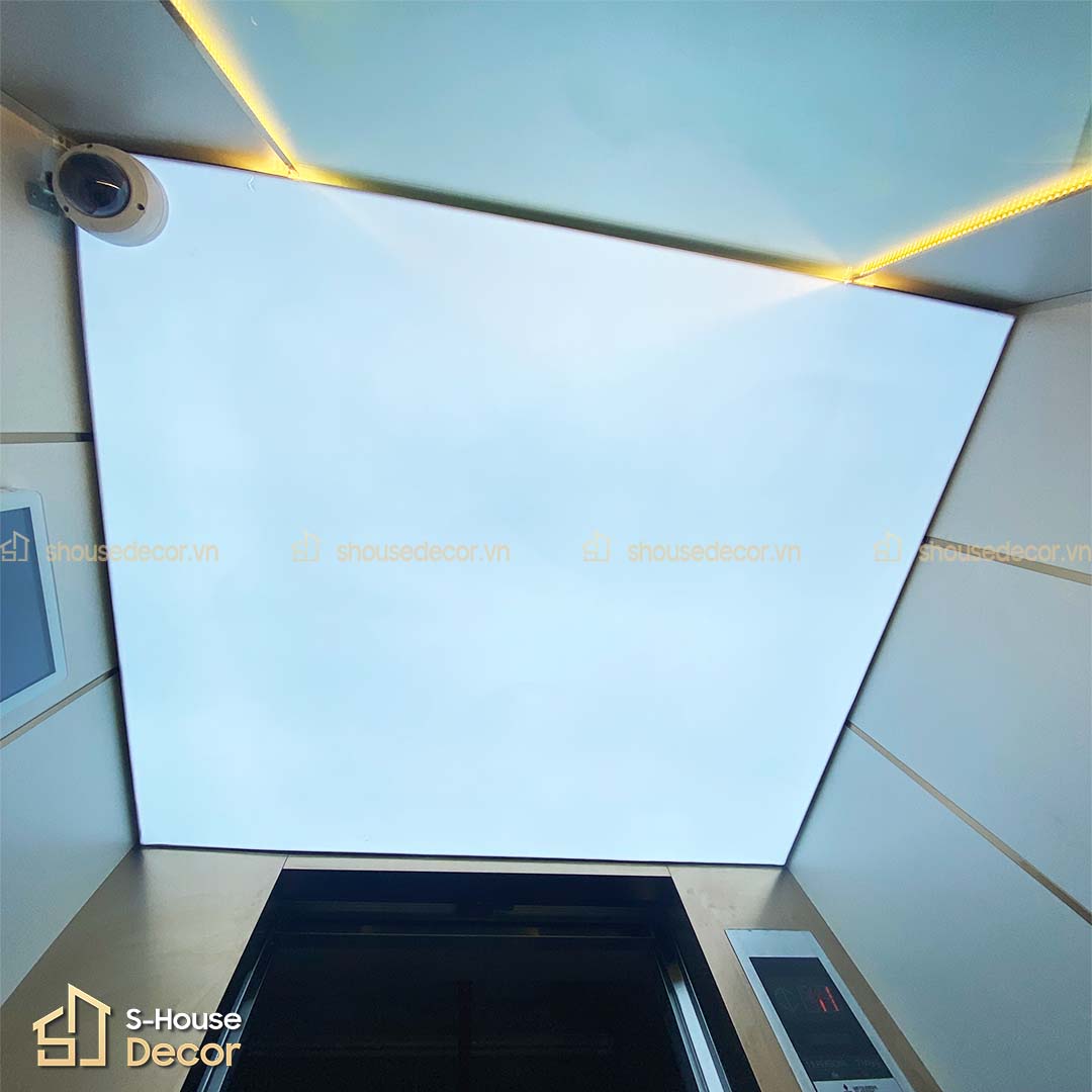 Góc nhìn từ dưới lên cho thấy hệ trần mica xuyên sáng tích hợp đèn LED đều khắp trần cabin thang máy, tạo không gian thoáng đãng và dễ chịu khi sử dụng.