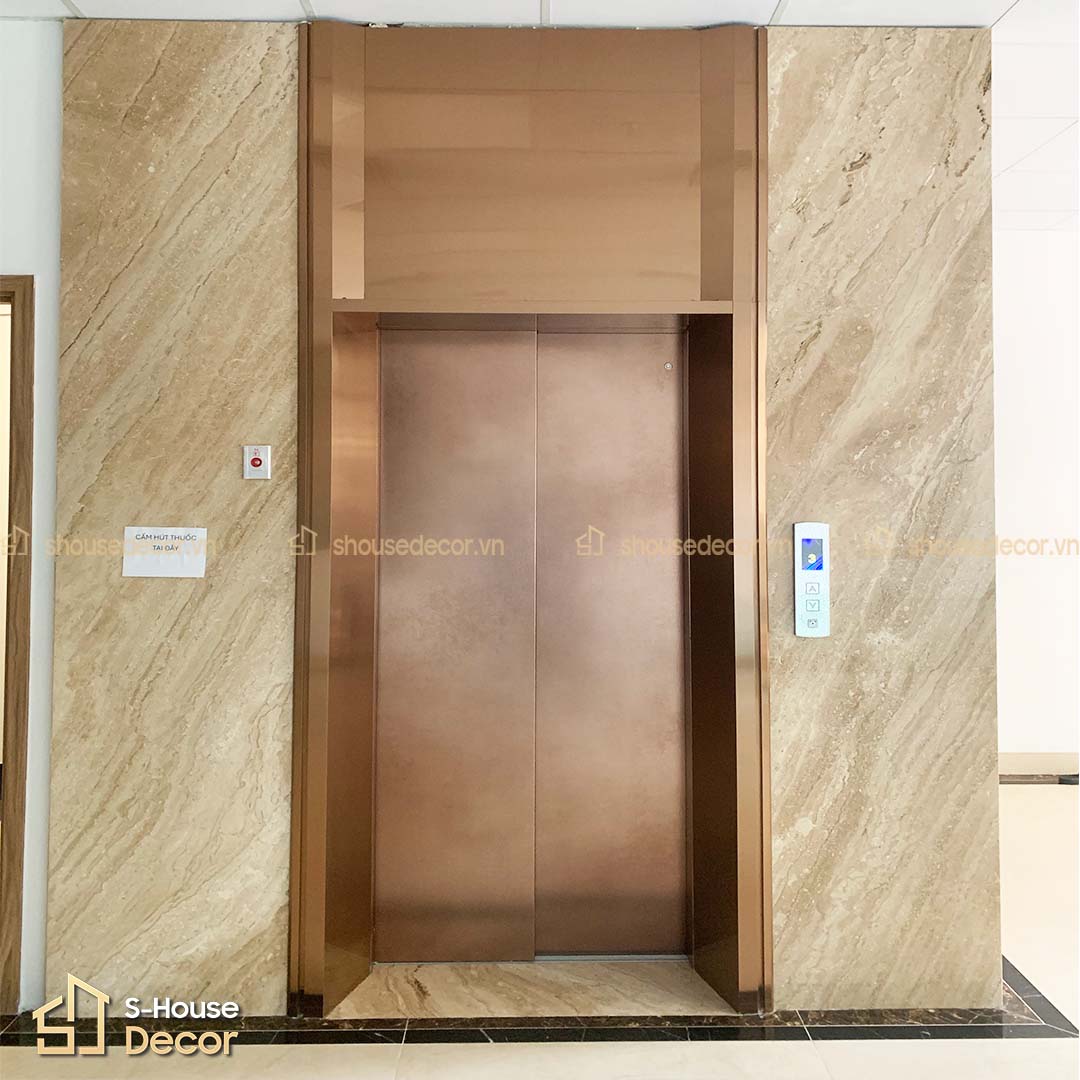 Cận cảnh lớp decal cửa tầng kết hợp viền inox vàng hồng bản rộng, đồng bộ thiết kế nội thất khu vực sảnh thang máy.