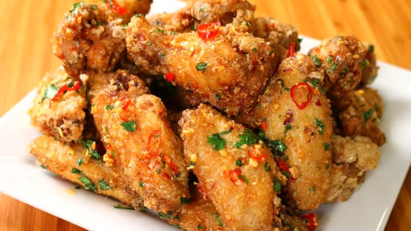 Rắc tỏi băm và rau mùi cắt nhỏ lên trên miếng gà