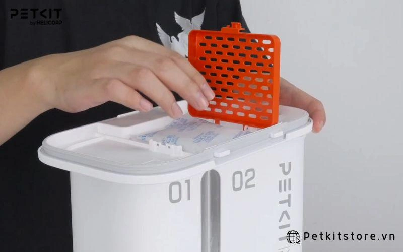 Cho gói hút ẩm vào trong nắp máy cho mèo ăn