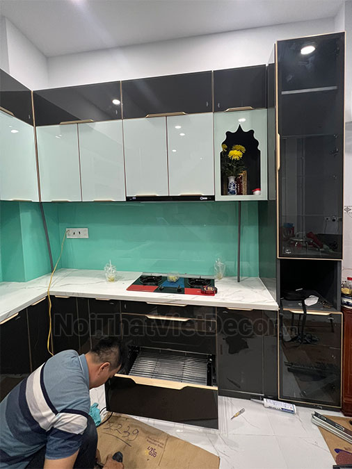 Tủ bếp hiện đại chữ L, khung inox 304 sơn tĩnh điện, cánh kính sơn màu viền nhôm, mặt đá marble vân mây, ốp tường kính cường lực - Hoàn thiện