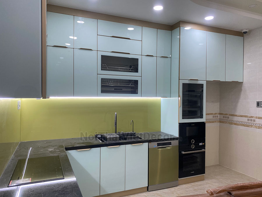 Tủ bếp hiện đại chữ L, khung inox 304 sơn tĩnh điện, cánh kính sơn màu viền nhôm, mặt bếp đá tự nhiên kim sa đen, ốp tường kính cường lực 8mm - Hoàn thiện