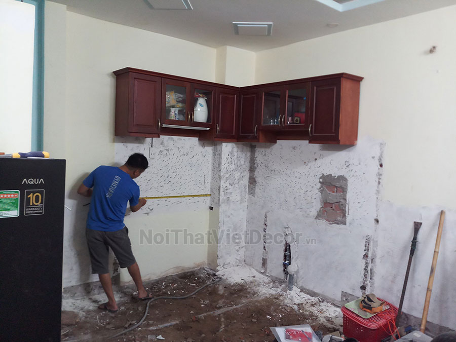 Tủ bếp hiện đại chữ L có vách che, gỗ công nghiệp nhựa WPB An Cường phủ laminate, mặt đá tự nhiên kim sa đen, ốp tường kính cường lực 8mm sơn màu - Hình thi công