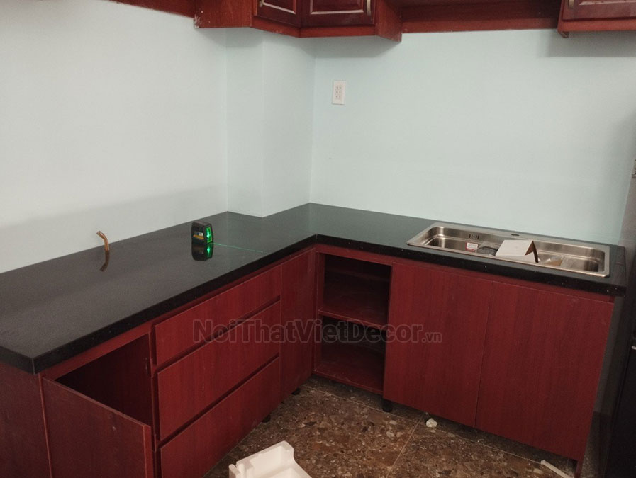 Tủ bếp hiện đại chữ L có vách che, gỗ công nghiệp nhựa WPB An Cường phủ laminate, mặt đá tự nhiên kim sa đen, ốp tường kính cường lực 8mm sơn màu - Hình hoàn thiện