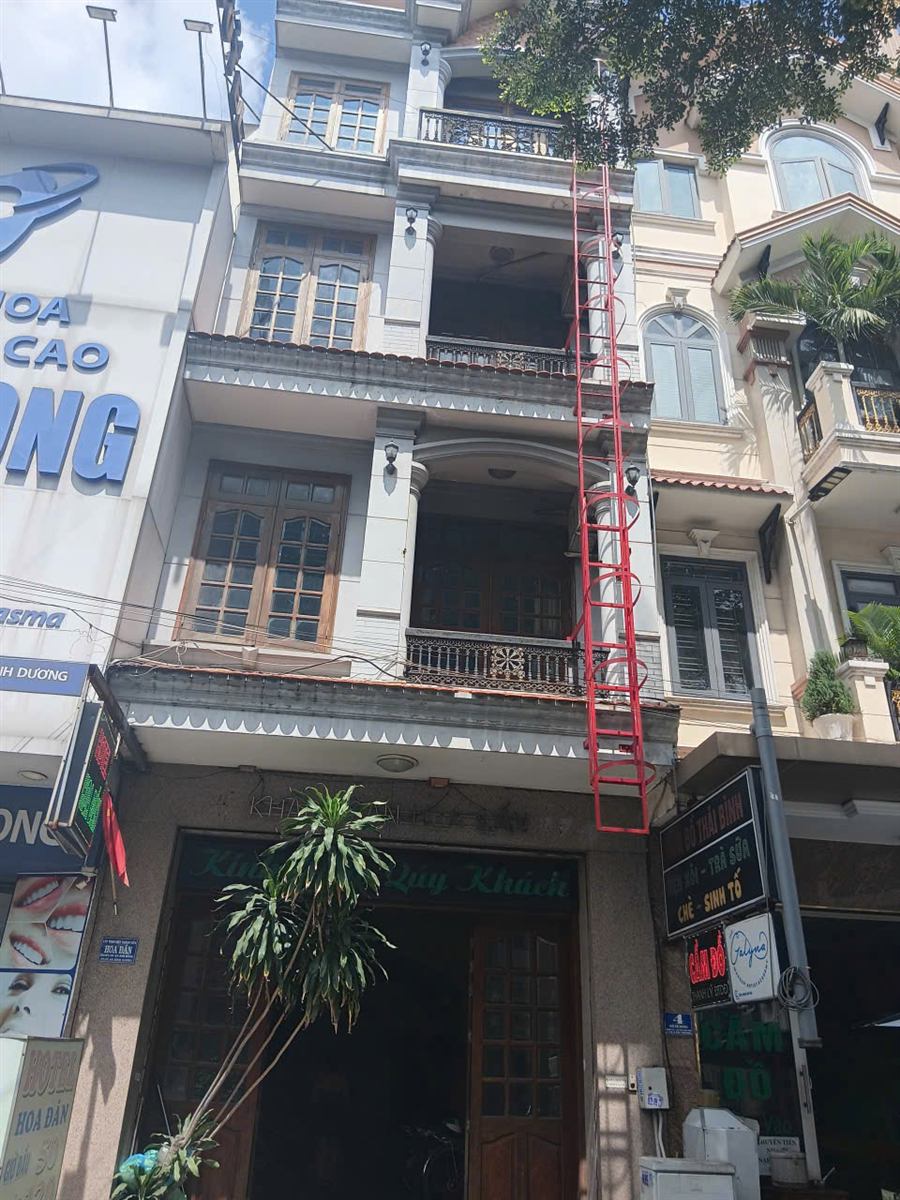 Nhà ống nhiều tầng có thang thoát hiểm bằng sắt sơn đỏ lắp bên ngoài