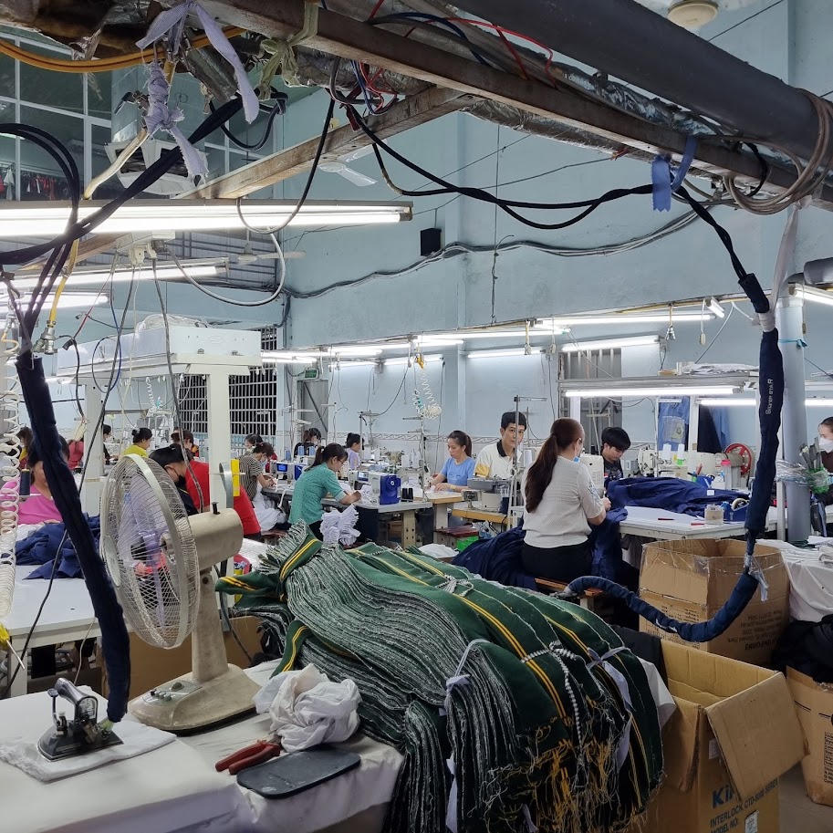 Dây chuyền may trong xưởng dệt may với công nhân và vải thành phẩm