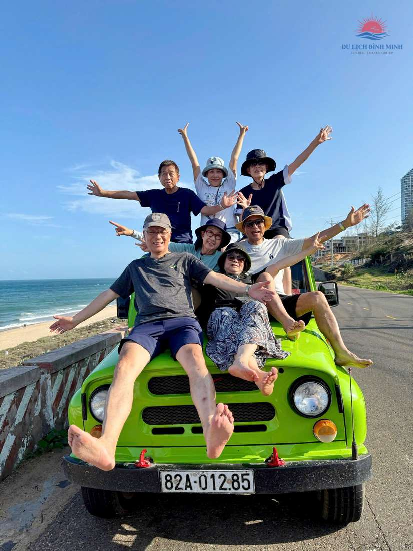 Đoàn khách vui vẻ tạo dáng trên xe jeep xanh lá trong tour đường ven biển Mũi Né của Du Lịch Bình Minh