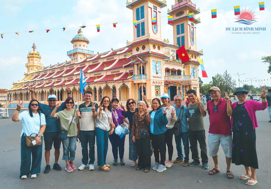 Đoàn khách Du Lịch Bình Minh chụp ảnh trước Tòa Thánh Cao Đài Tây Ninh với hai tháp chuông và dây cờ tam thanh