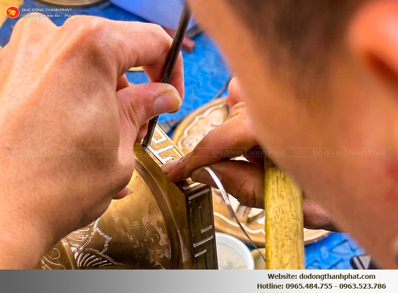 Cận cảnh kỹ thuật khảm vàng bạc trên bề mặt cong của chân nến đồng đỏ nồi hè