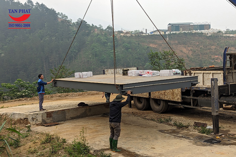 Cẩu vận chuyển hạ cầu cân 100 tấn 12x3m xuống vị trí lắp đặt theo yêu cầu.