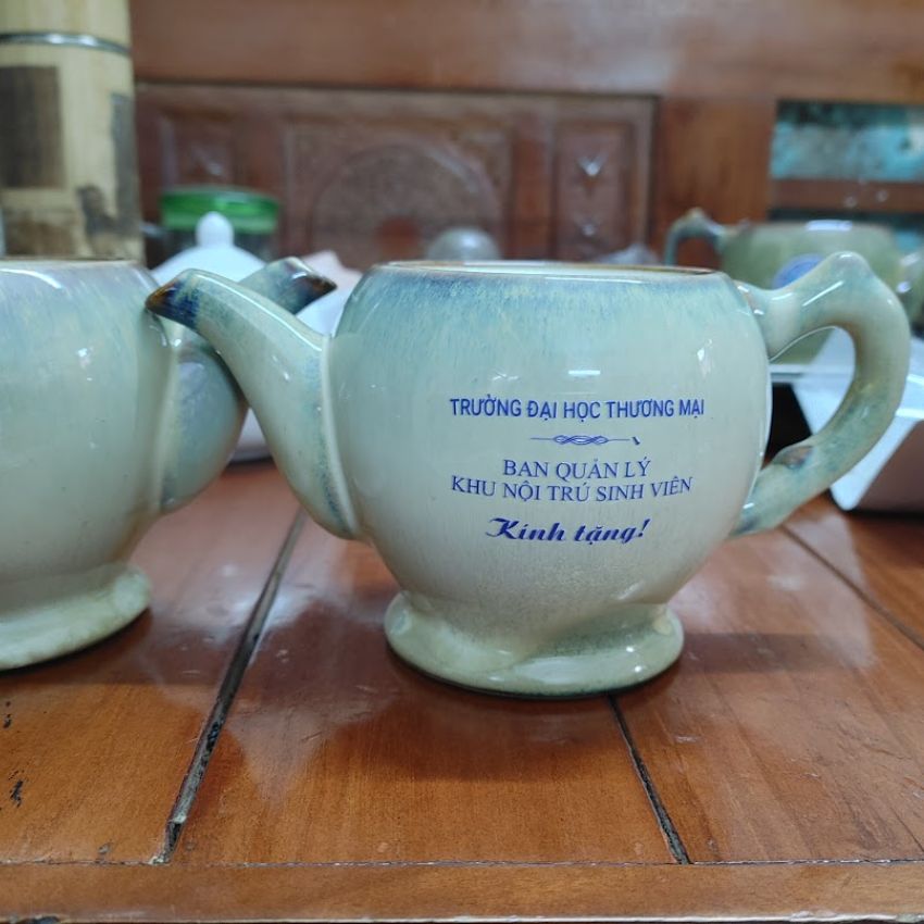 Chiếc ấm trà gốm màu xanh nhạt in dòng chữ Đại học thương mại