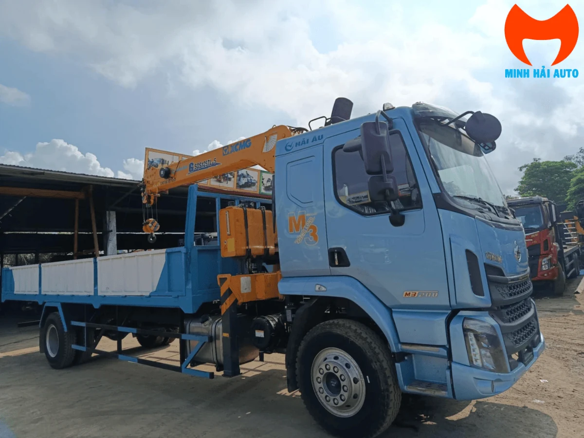 Xe tải Chenglong M3 cabin xanh dương gắn cẩu tự hành XCMG màu vàng cam phía sau cabin, thùng lửng, nhìn chéo từ phía trước