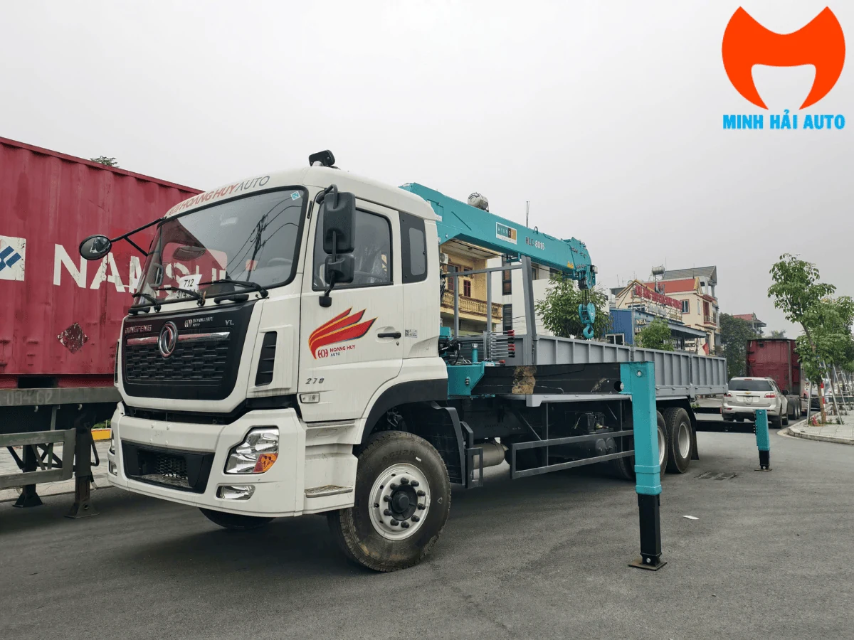 Xe tải Dongfeng ba chân cabin trắng gắn cẩu tự hành màu xanh ngọc nhãn HLC-8016, thùng lửng dài, chân chống hạ tại bãi