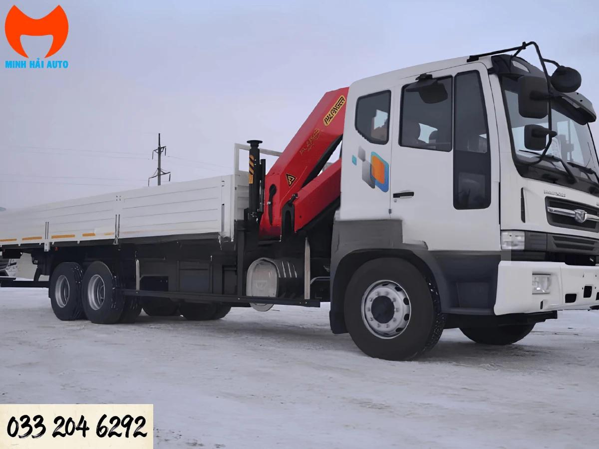 Xe tải Daewoo ba chân màu trắng, thùng lửng dài, cẩu gập Palfinger đỏ đặt sau ca-bin với chân chống thu gọn