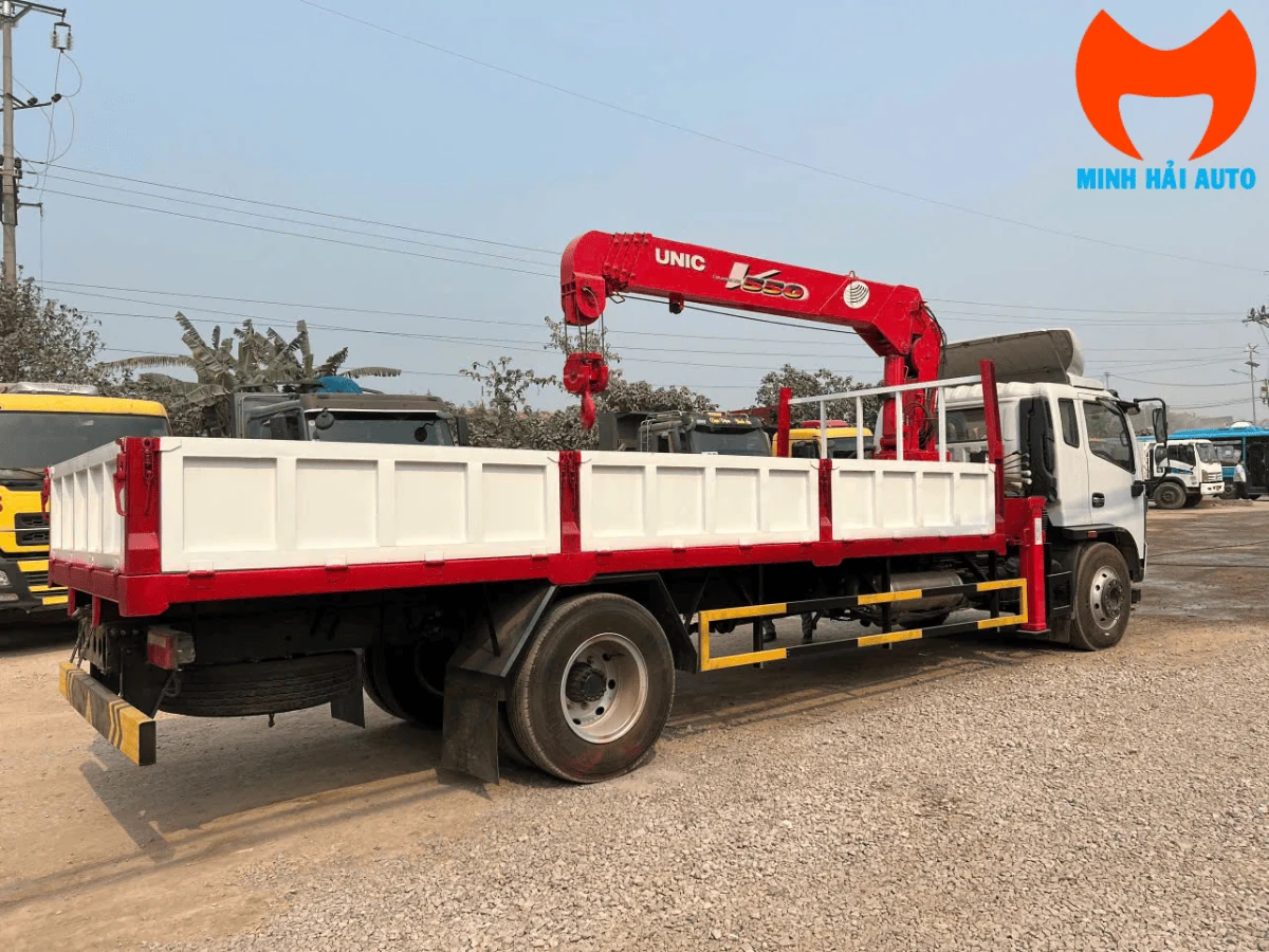 Cần cẩu UNIC màu đỏ gập gọn đặt sau ca-bin xe Dongfeng, nhìn từ phía sau xe thấy rõ thùng lửng và cụm chân chống