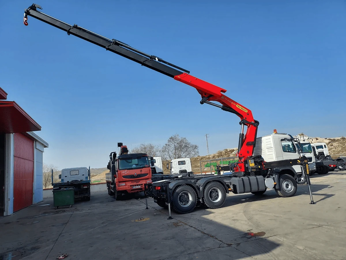 Cẩu gập khúc Palfinger màu đỏ đang duỗi cần gần hết tầm, các đoạn cần màu đen lồng nhau, chụp tại xưởng