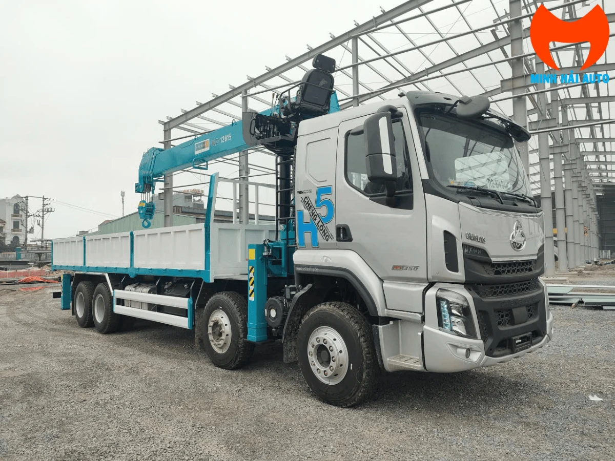 Xe Chenglong H5 bốn chân với cần cẩu xếp gọn nằm dọc phía trên thùng lửng, nhìn chéo từ phía trước bên phải