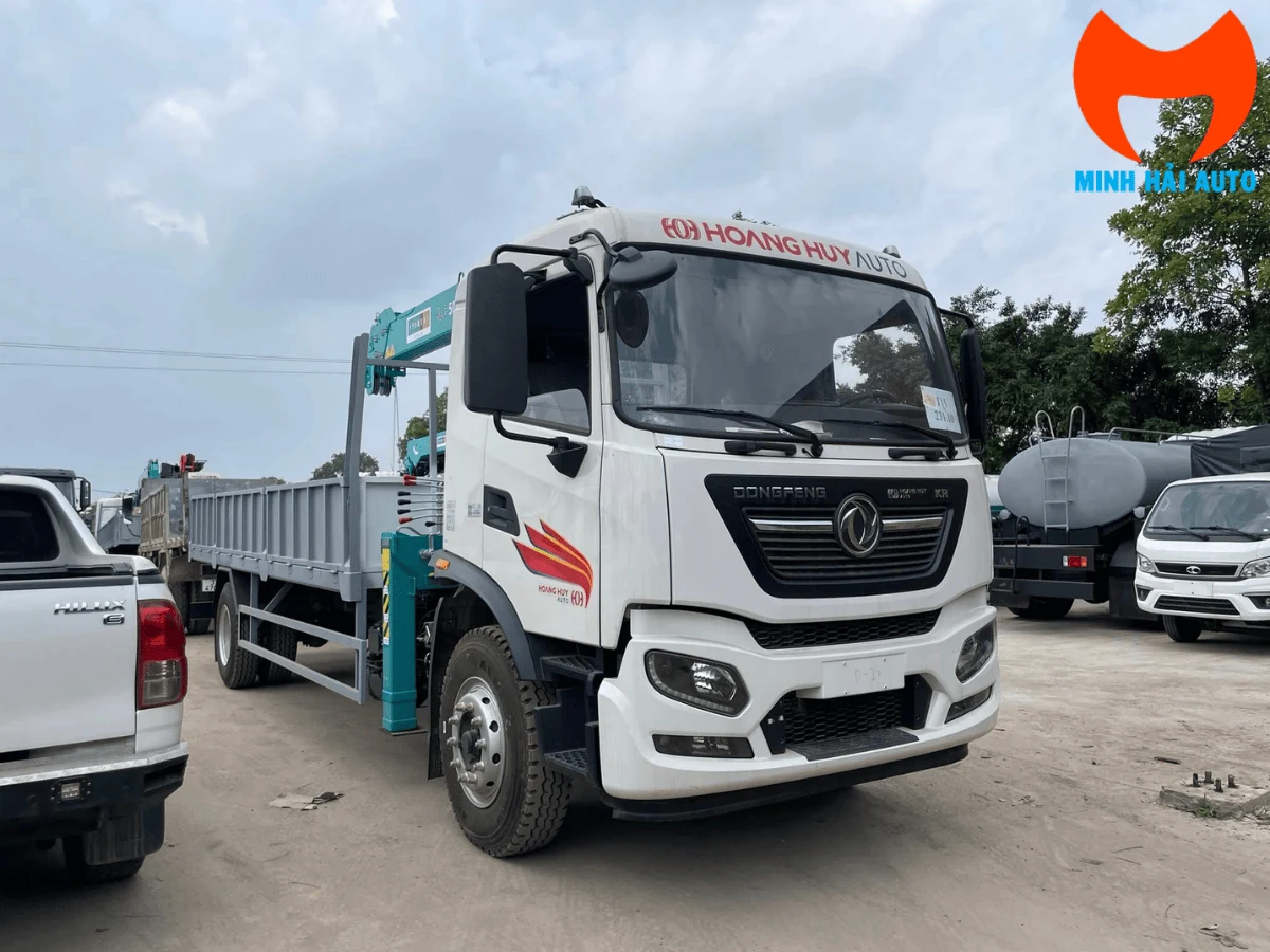 Xe tải Dongfeng cabin trắng gắn cẩu tự hành màu xanh ngọc, thùng lửng thành mở, đỗ tại bãi xe cùng các xe chuyên dùng khác