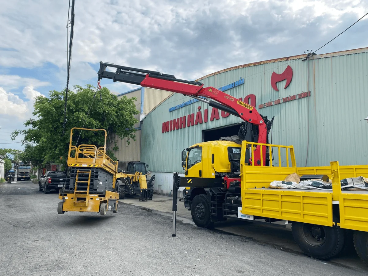 Xe Isuzu FVZ gắn cẩu Palfinger đang nâng thiết bị tại sân xưởng