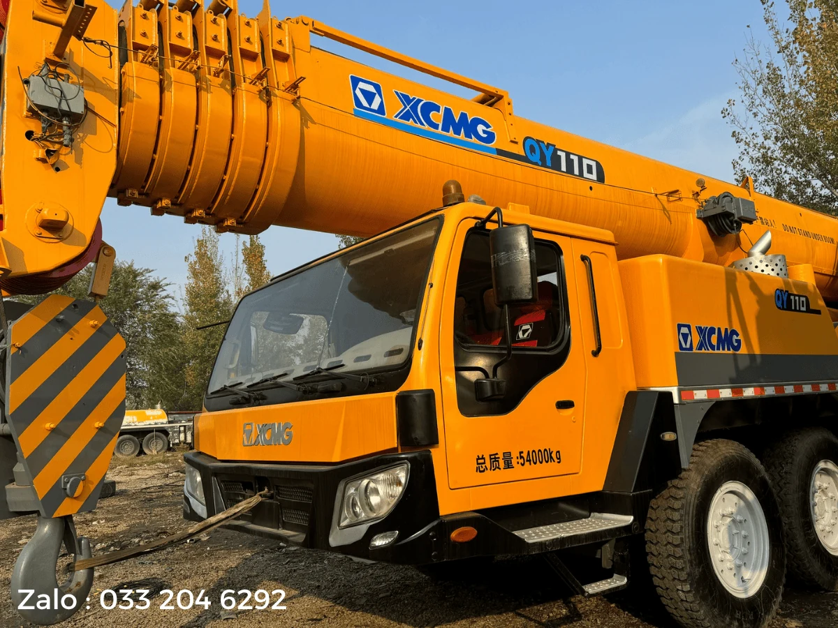 Nhãn QY110 và logo XCMG trên cần chính xe cẩu bánh lốp, phía dưới là cabin lái ghi tổng khối lượng 54000 kg