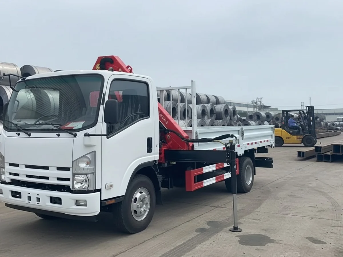 Xe tải Isuzu gắn cẩu gập đỗ tại bãi thép cuộn, chân chống đã hạ xuống nền