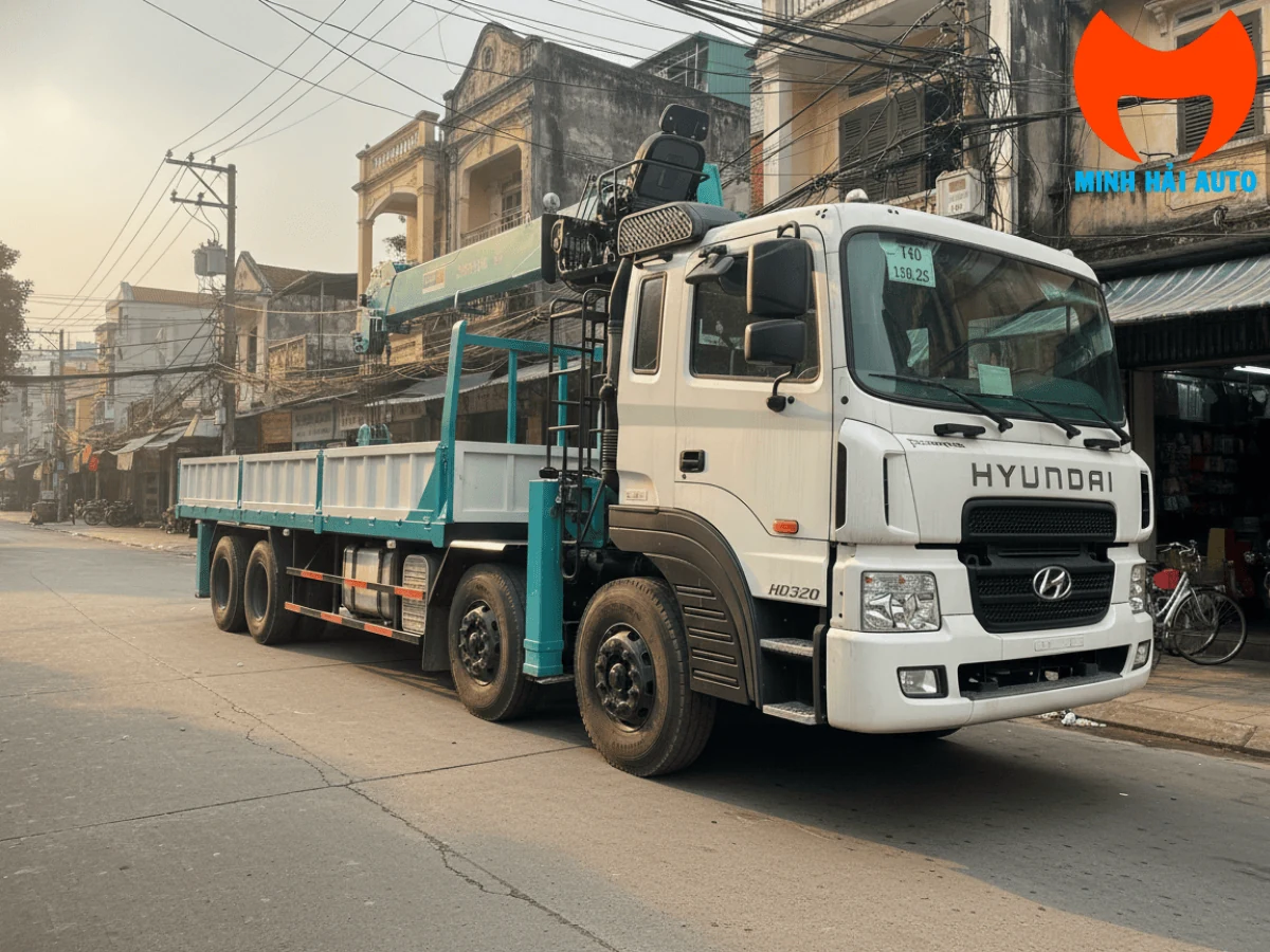 Xe tải Hyundai HD320 bốn chân cabin trắng gắn cẩu tự hành màu xanh ngọc có ghế điều khiển cao, thùng lửng, đỗ trên phố