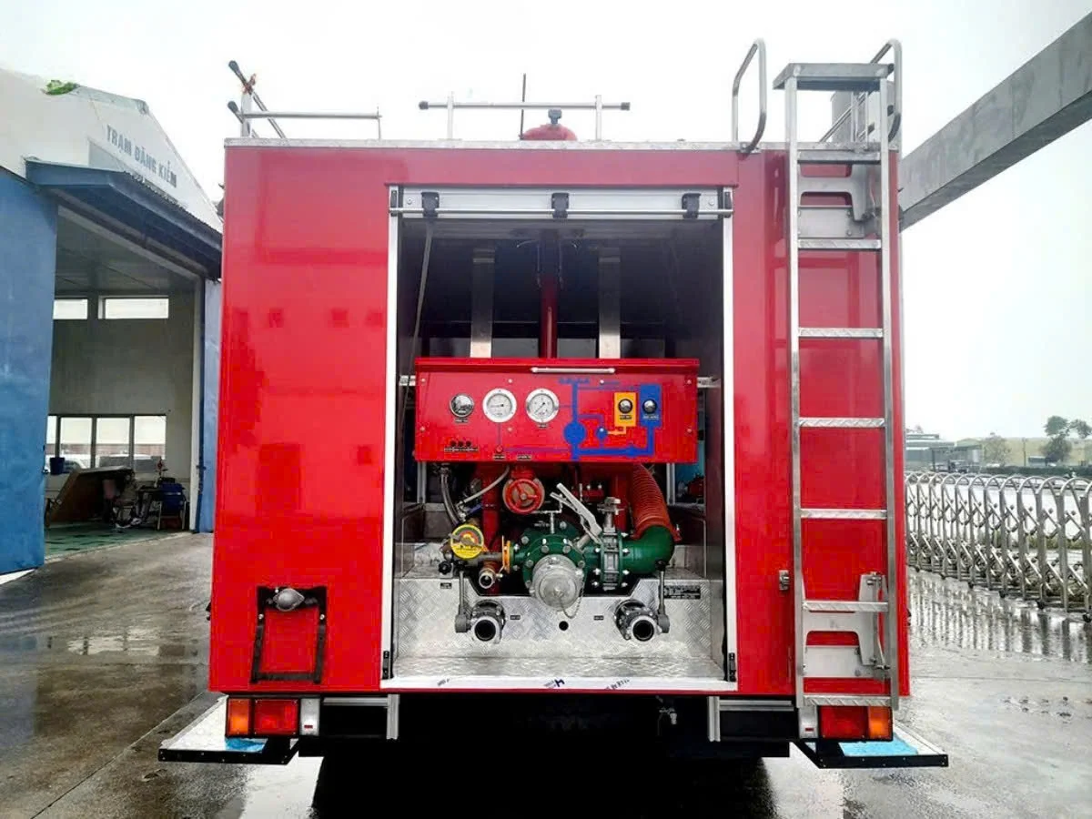 Khoang bơm phía sau xe chữa cháy Isuzu 8 khối mở cửa cuốn, thấy bảng đồng hồ áp suất, cụm van và thang leo, chụp tại trạm đăng kiểm