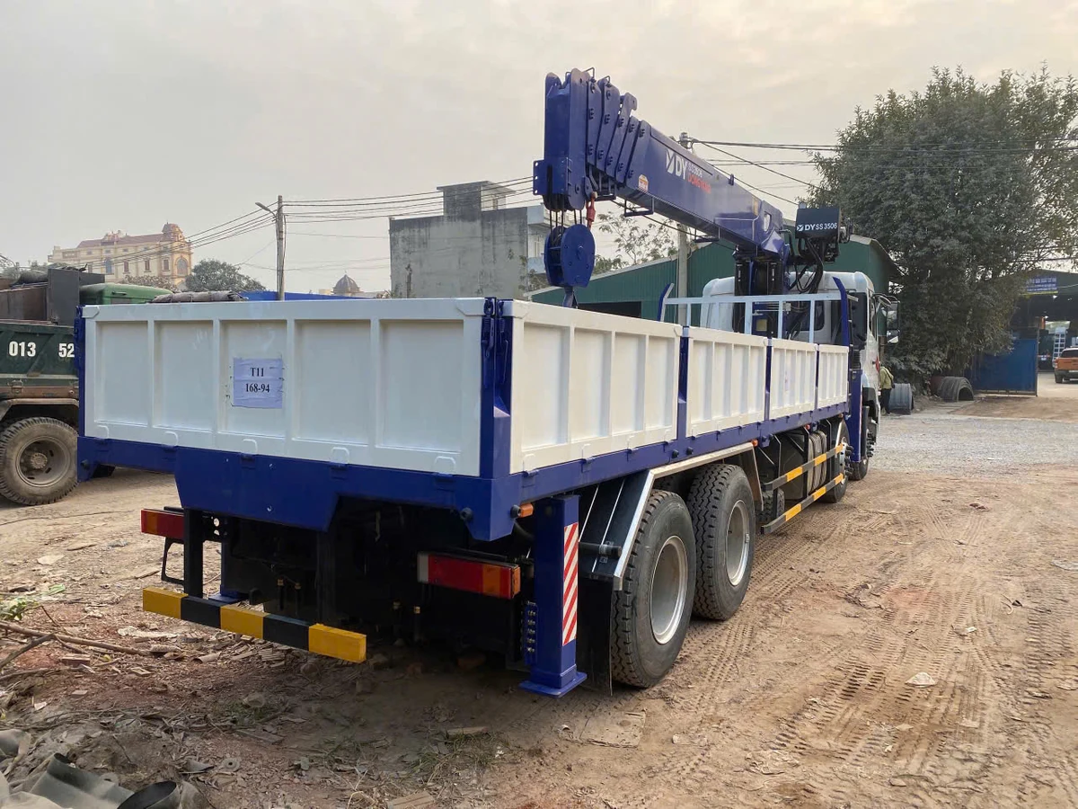 Đuôi xe cẩu Dongyang SS3506 nhìn từ phía sau, thấy chân chống sau hạ xuống đất và thùng lửng thành cao