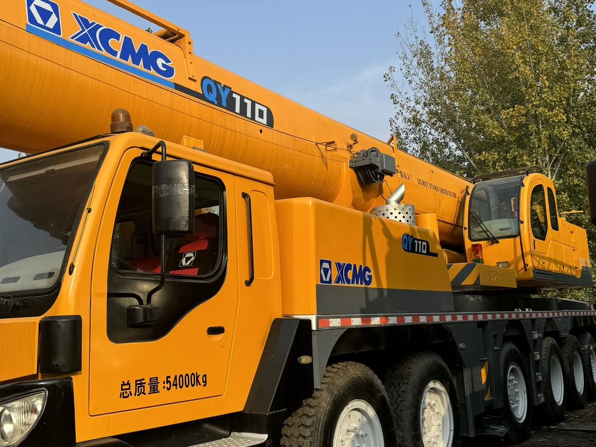 Thân xe cẩu XCMG QY110KH nhìn ngang thấy rõ năm trục bánh và dòng chữ tổng khối lượng 54000 kg trên cửa cabin