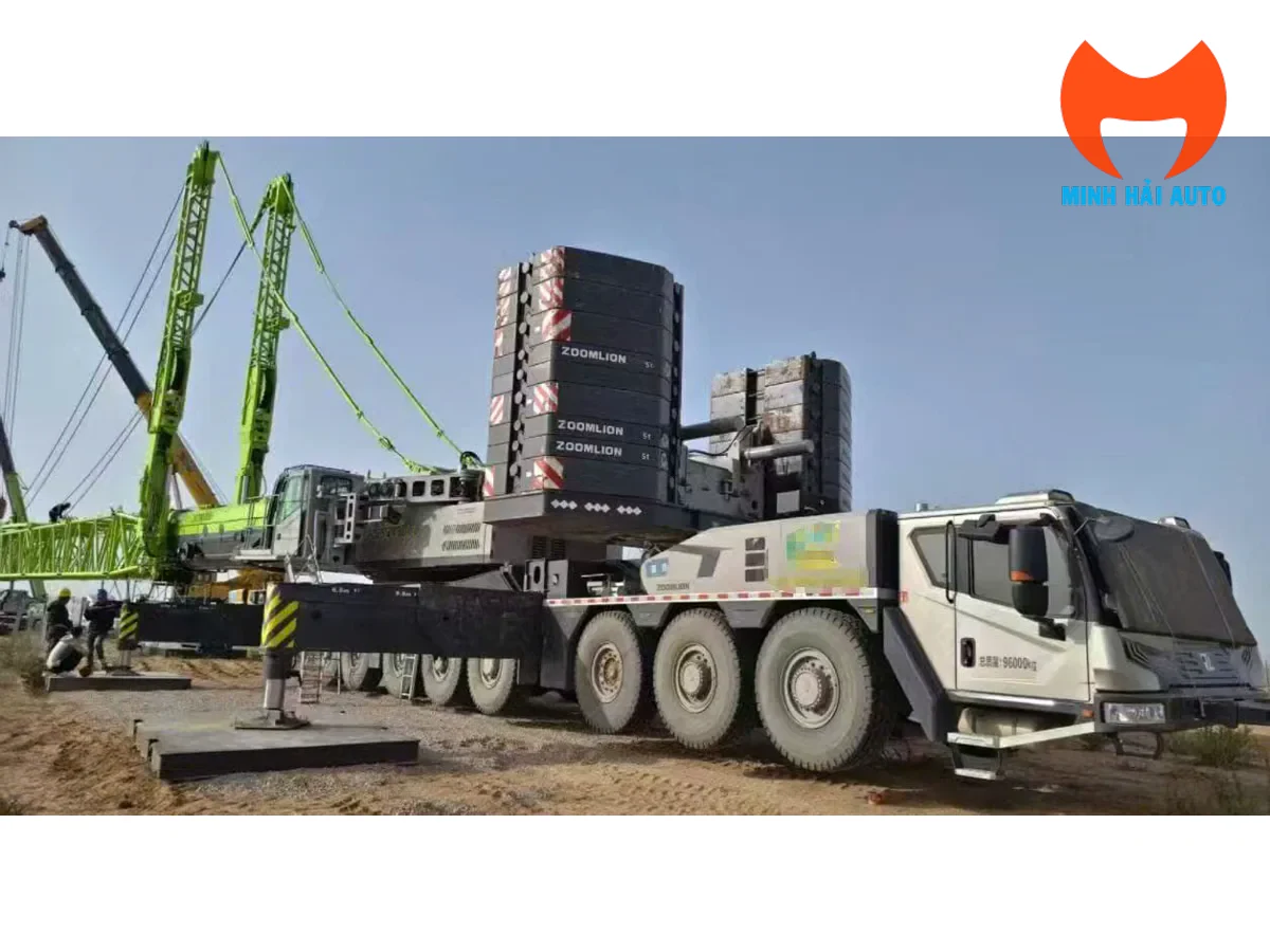 Xe cẩu bánh lốp Zoomlion nhiều trục đang mở chân chống trên tấm kê tại công trường, phía sau là các khối đối trọng xếp chồng