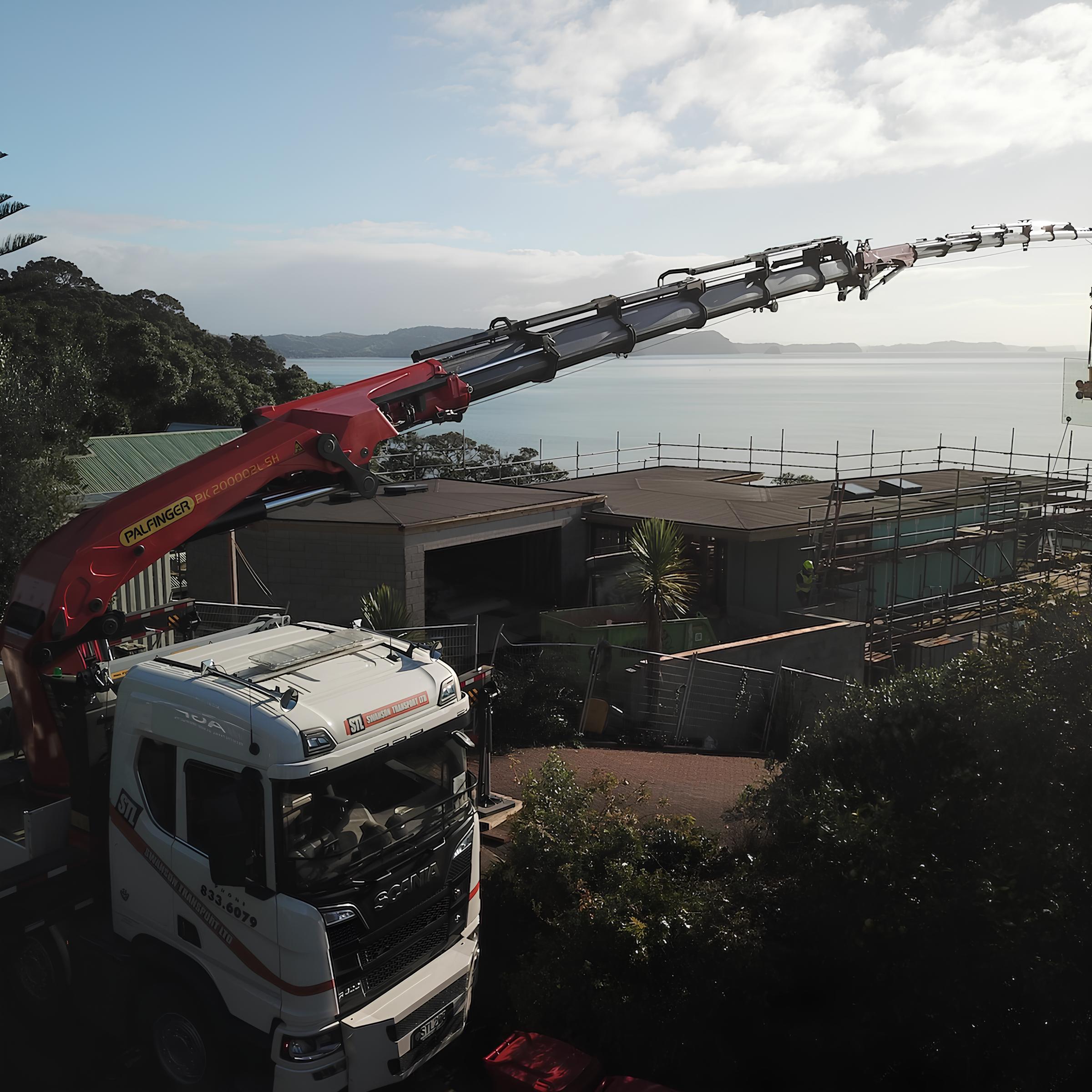 Cẩu gấp khúc Palfinger 40 tấn PK 200002 đang làm việc tại một công trường xây dựng lớn.