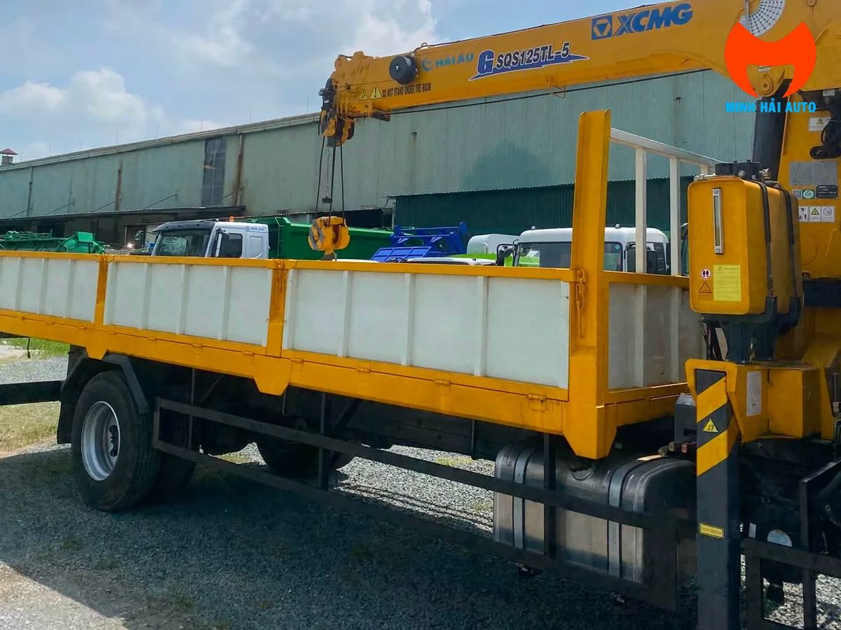 Thùng lửng vàng và cần cẩu XCMG G-SQS125TL-5 trên xe Chenglong M3 nhìn từ hông sau