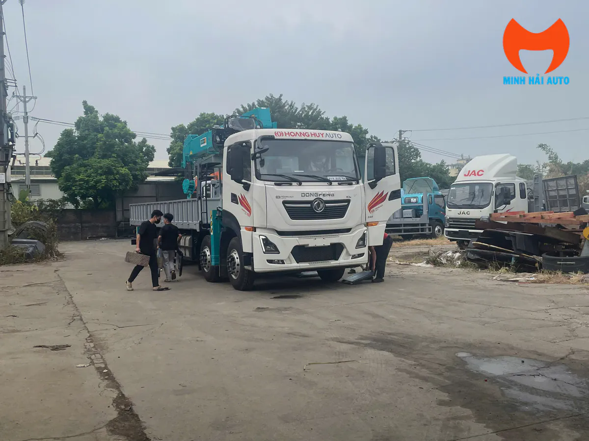 Hai kỹ thuật viên kiểm tra phần gầm phía trước của xe tải nhiều cầu đã gắn cẩu ống lồng tại sân xưởng