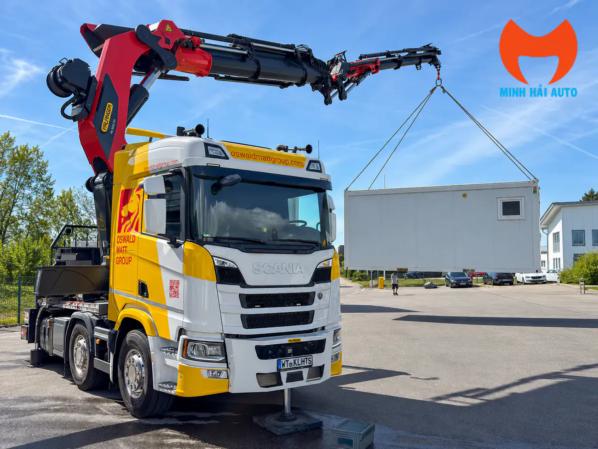 Xe Scania vàng trắng gắn cẩu Palfinger nâng một mô đun cabin tại bãi ngoài trời