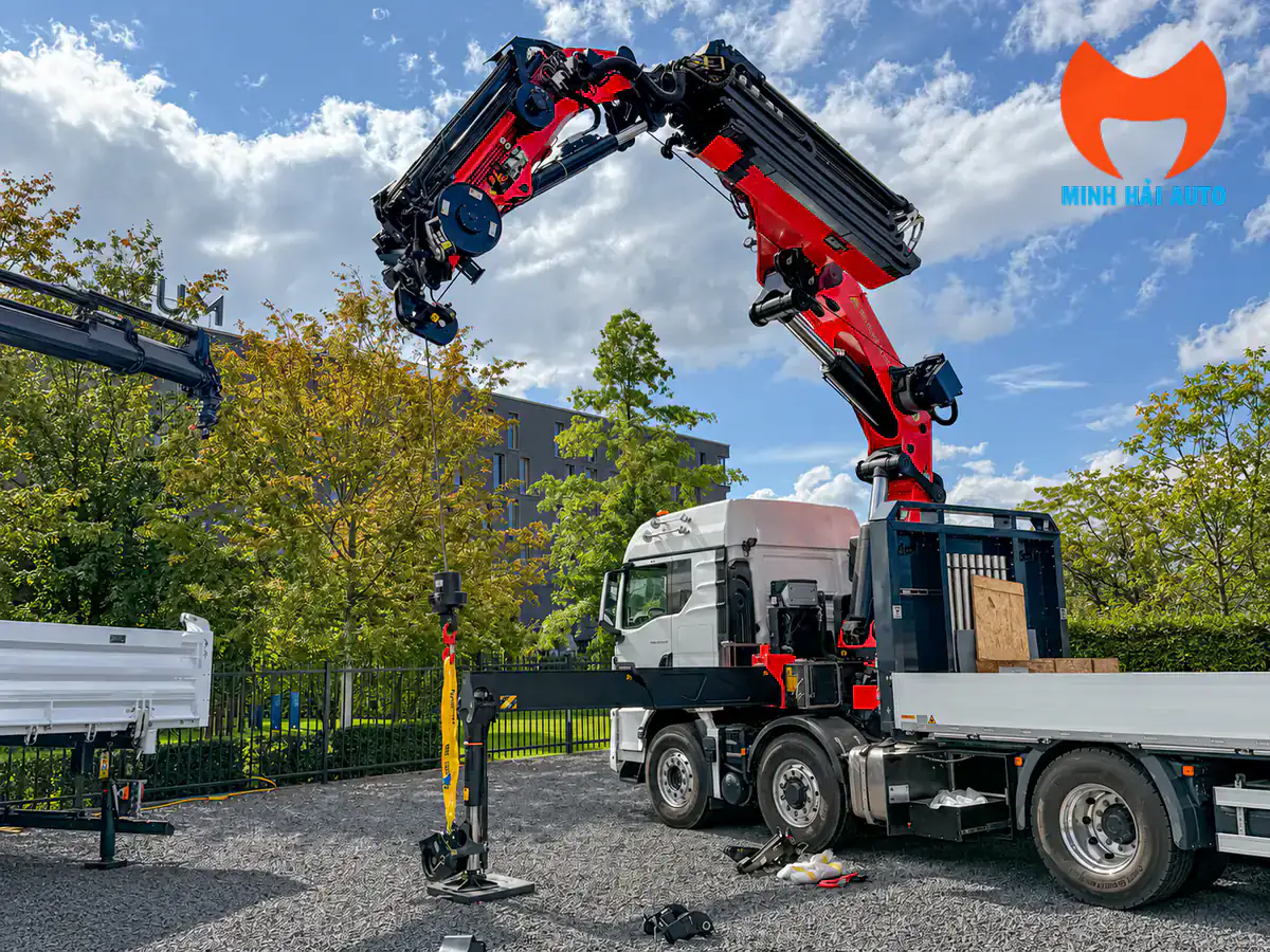 Xe tải trắng gắn cẩu gập Palfinger đỏ đen triển khai cần tại bãi ngoài trời