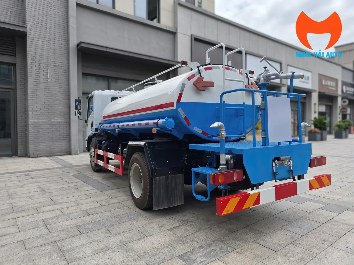 Phía sau xe bồn nước trắng xanh với sàn thao tác, đường ống và súng phun